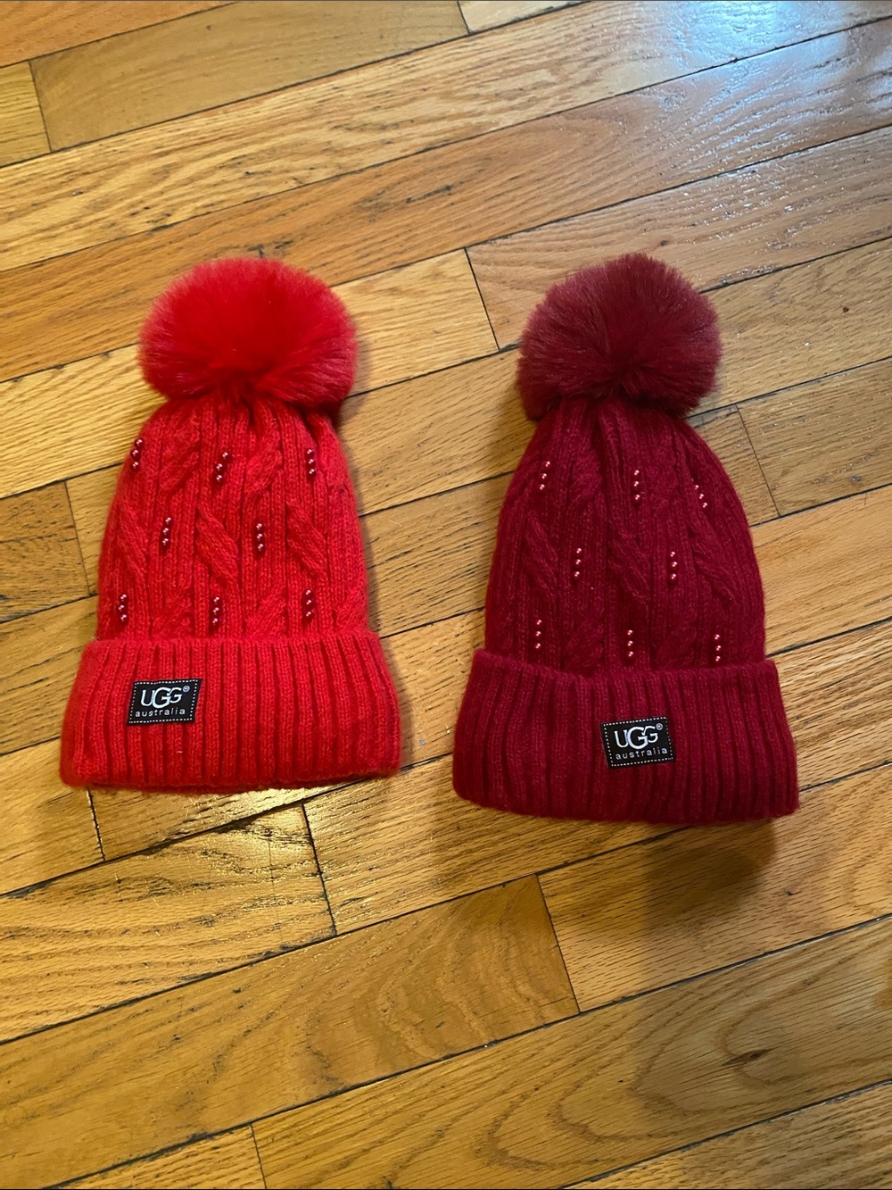 2 pieces UGG Kids Cable Knit Pom Beanies in Bright Red and Burgundy
